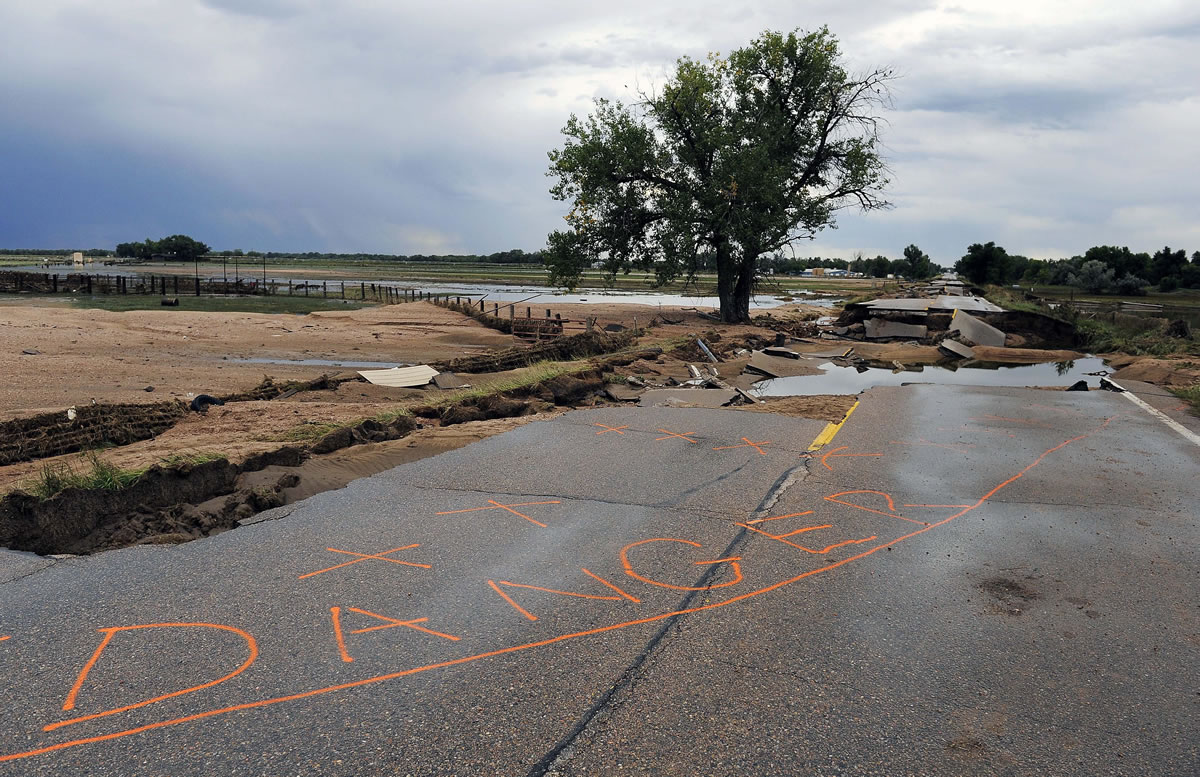 Danger is spray-painted on a damaged section of Old Highway 34 in Loveland, Colo., on Wednesday.