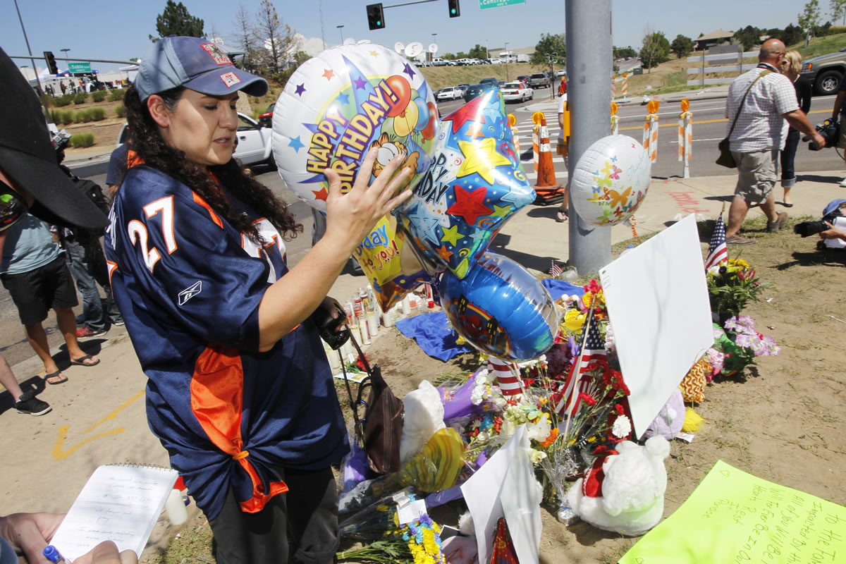 Shelly Fradkin, the mother of a friend of shooting victim Alex Sullivan, places balloons to mark Sullivan's birthday at a makeshift memorial across from the Century 16 theatre east of the Aurora Mall in Aurora, Colo., on Saturday.