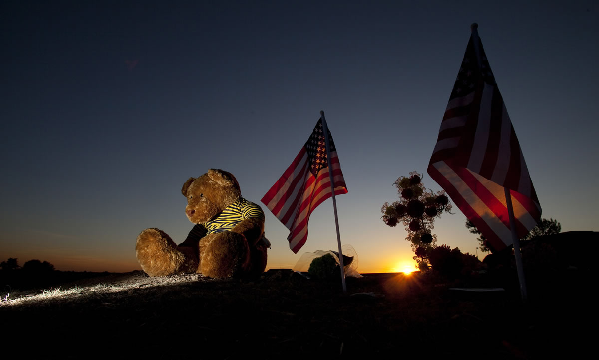Just before dawn, a teddy bear, American flags and candles form a makeshift memorial in a field across the street from the Century Theater on Saturday, the day after alleged shooter James Holmes killed at least 12 people and injured dozens more at a midnight premiere of &quot;The Dark Knight Rises&quot; Batman movie, in Aurora, Colo.