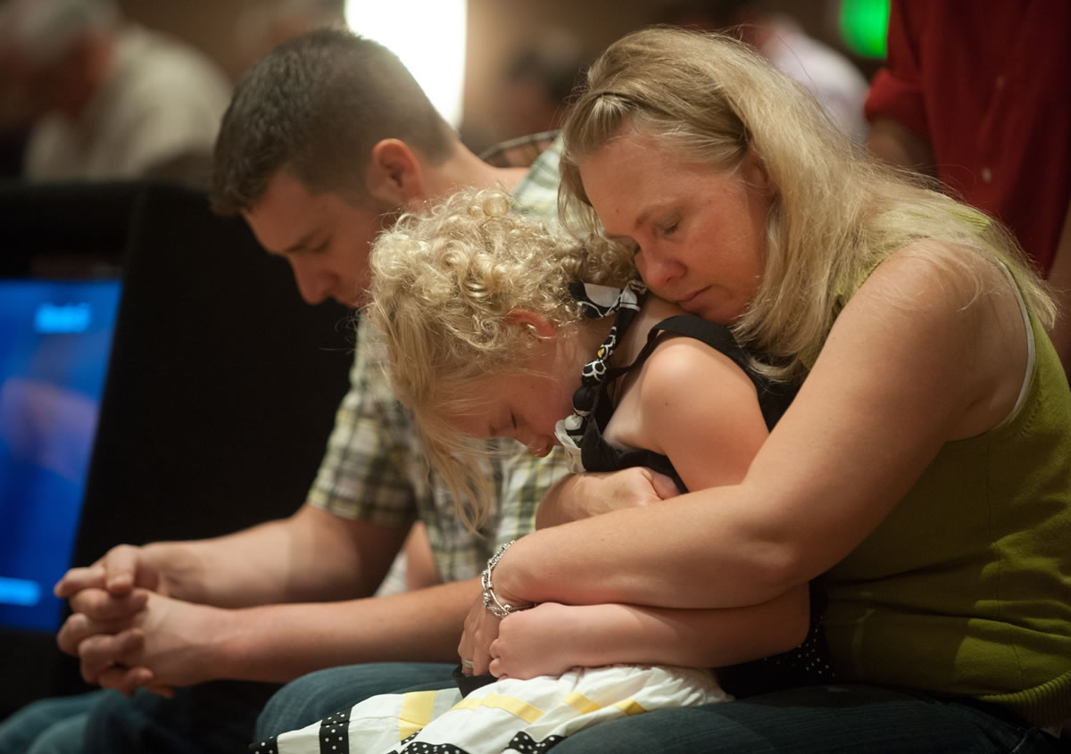 Lara Stern, right, holds her daughter, Alana, 8, and husband Samuel Stern on Sunday during a community prayer service at First Baptist Church near Colorado Springs, Colo.