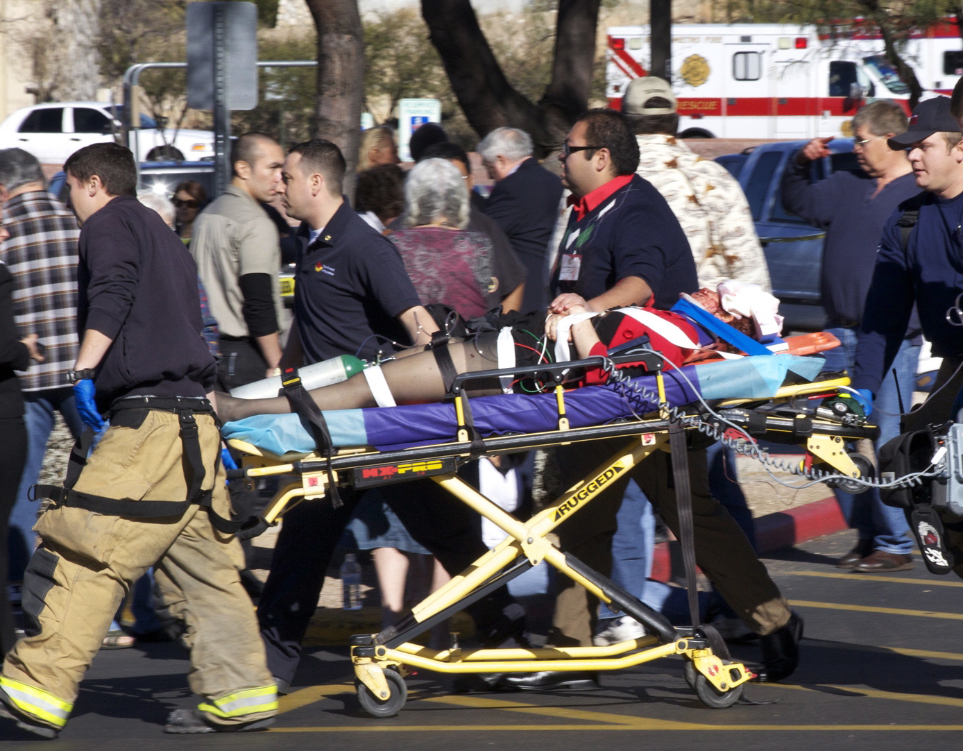 Emergency personnel and Daniel Hernandez, an intern for U.S. Rep. Gabrielle Giffords, second right, move Giffords after she was shot in the head outside a shopping center in Tucson, Ariz.