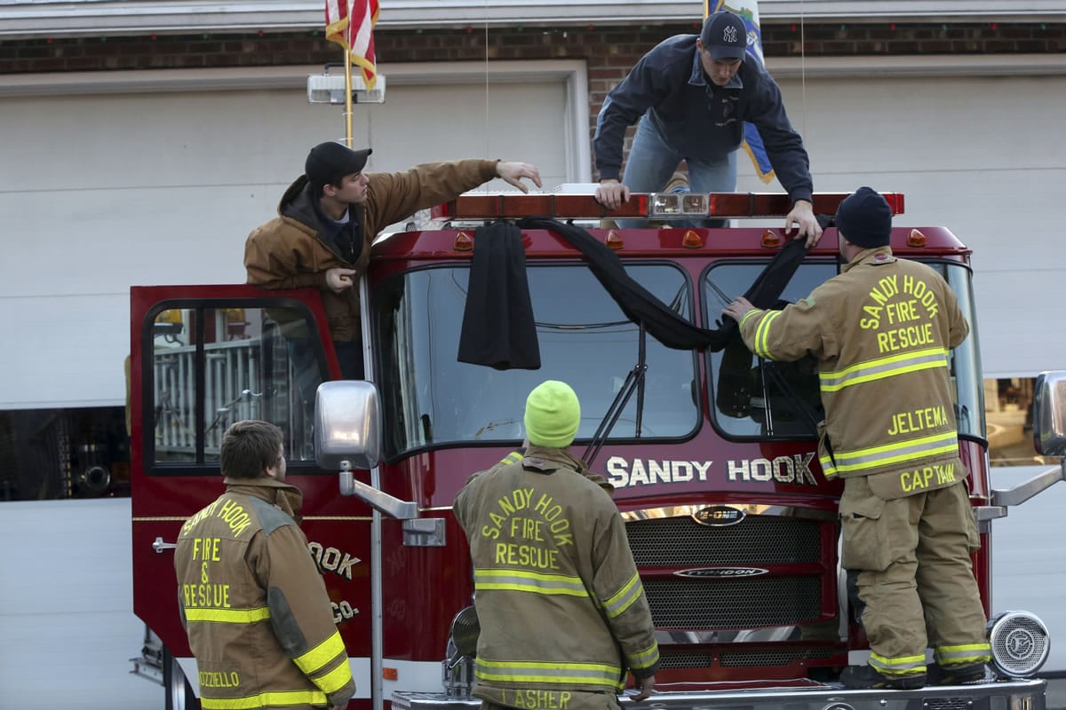 Sandy Hook firefighters hang bunting on their firetruck, Saturday, Dec. 15, 2012 in Sandy Hook village of Newtown, Conn.