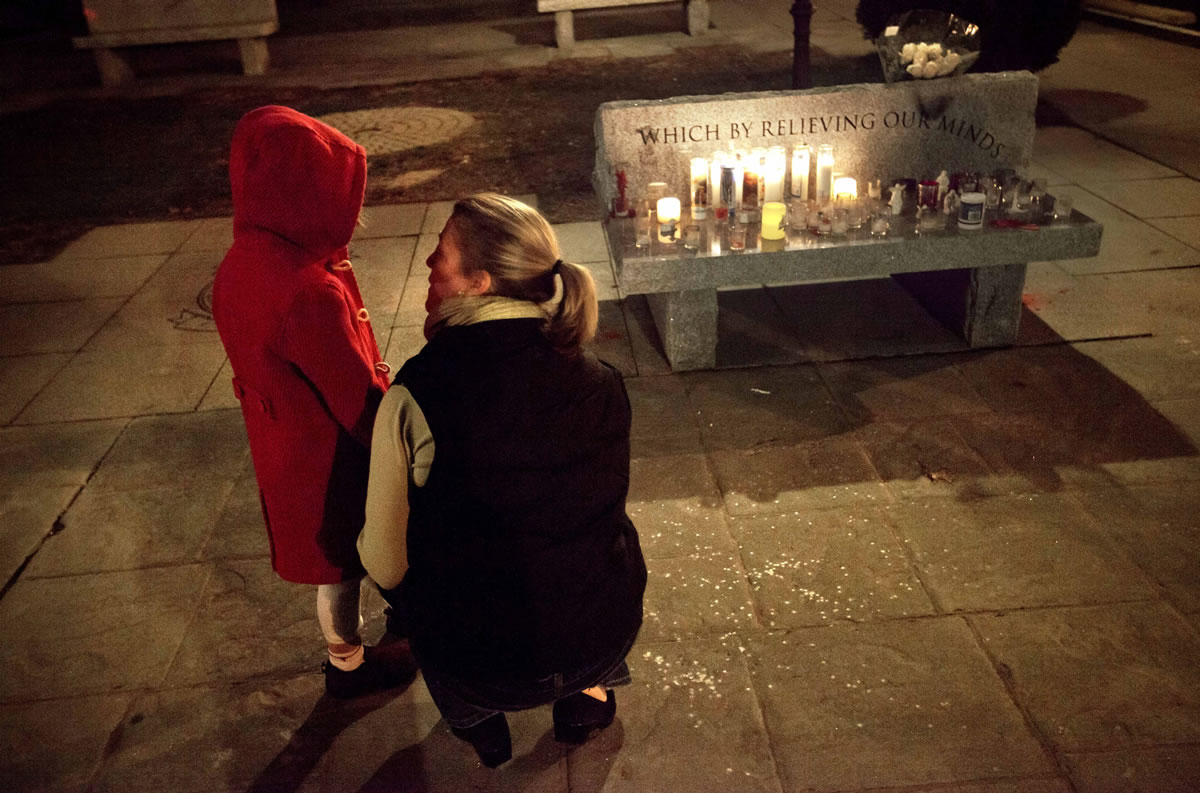 Rhonda Eleish, right, talks to her daughter Kari Ergmann, 6, both of Bridgewater, Conn., next to a candlelight vigil outside the Edmond Town Hall, Saturday, Dec. 15, 2012, in Newtown, Conn. Eleish suspects her daughter knew one of the victims of Friday's shooting at Sandy Hook Elementary School in Newtown that killed 26 people, including 20 children.