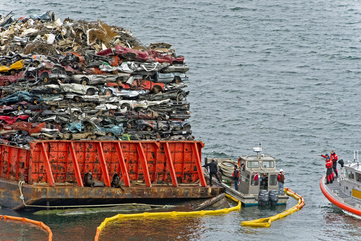 Emergency responders work to stabilize a listing barge laden with scrap car hulks anchored near the northern shore of Commencement Bay in Tacoma in late February.