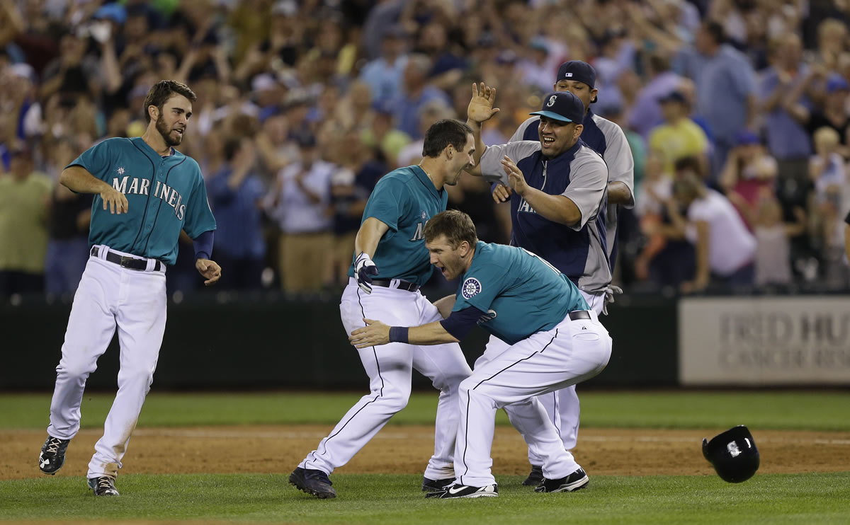 Seattle Mariners' Mike Zunino, center, is greeted by teammates after he hit a walk-off RBI single to give the Mariners a 5-4 win in the 10th inning against the Chicago Cubs on Friday.