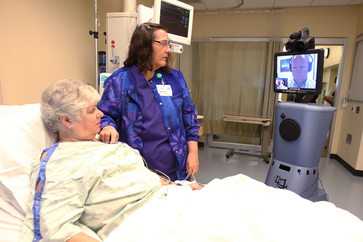 Photos by Andy Tullis/The Bulletin
Volunteer Anita Boucher lies in a hospital bed Wednesday in Redmond, Ore., while Dr. Kevin Sherer in Bend Ore., listens to her heart with the help of ICU nurse Emilie Bonney and telemedicine robot Roda.