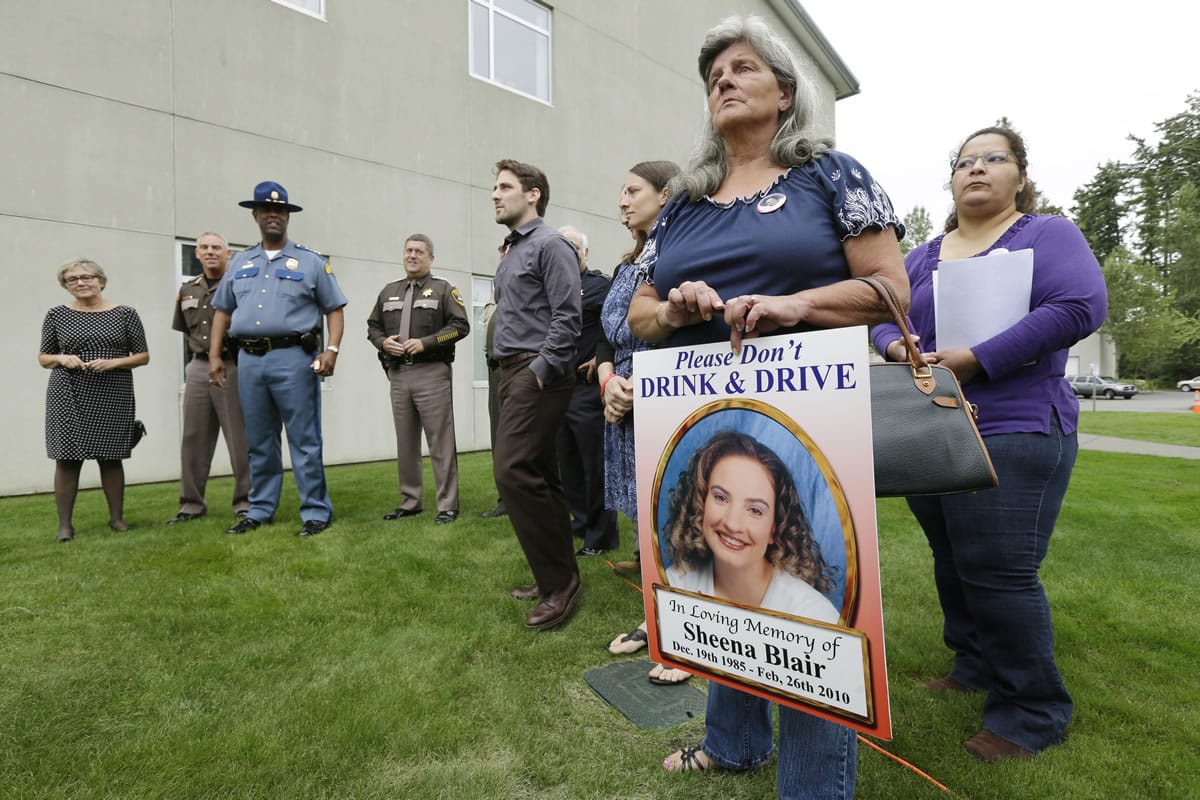 Carol Jones-Blair, second from right, holds a poster of her daughter Sheena Blair, who was killed in an accident with a wrong-way driver in 2010, as she attends a bill-signing ceremony Thursday in Tacoma. Washington Gov.