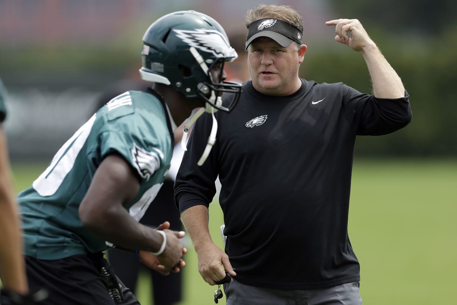 Philadelphia Eagles coach Chip Kelly, right, speaks with Ifeanyi Momah at the NFL football team's training camp in Philadelphia, Tuesday, Aug. 13, 2013.