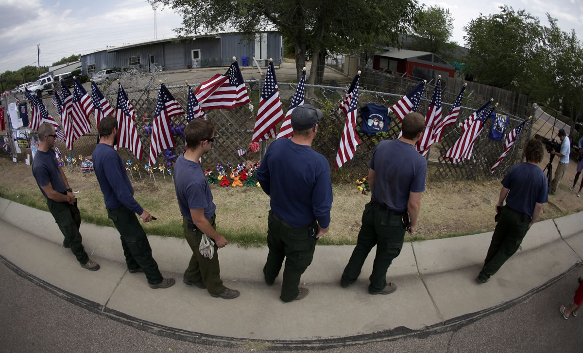 Members of a fire crew pay their respects Thursday at a memorial to 19 fallen firefighters outside the Granite Mountain Interagency Hotshot Crew fire station in Prescott, Ariz.