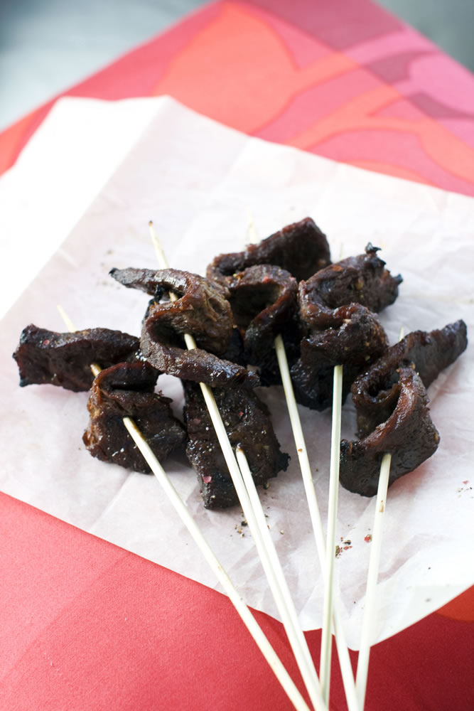 Sweet and Sticky Slow-Cooked Short Ribs are served on skewers.
