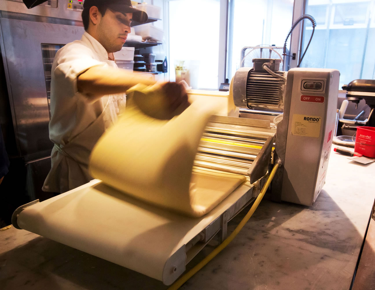 This June 3 photo shows a worker putting dough through a roller to make Cronuts, croissant-donut hybrid, at New York's Dominique Ansel Bakery in New York.