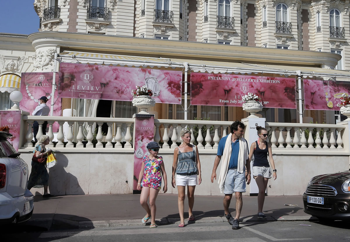People walk by the Carlton hotel in Cannes, southern France, the scene of a daylight raid on Sunday.