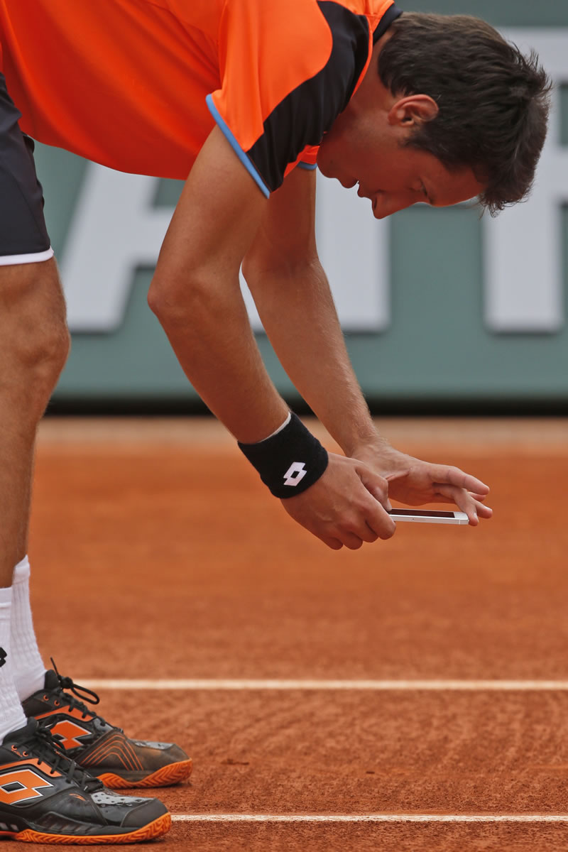 Ukraine's Sergiy Stakhovsky takes a picture with his smart phone after contesting the decision of the umpire to call the ball in, in his first round match against Richard Gasquet of France at the French Open tennis tournament, in Roland Garros stadium in Paris, Monday, May 27, 2013.