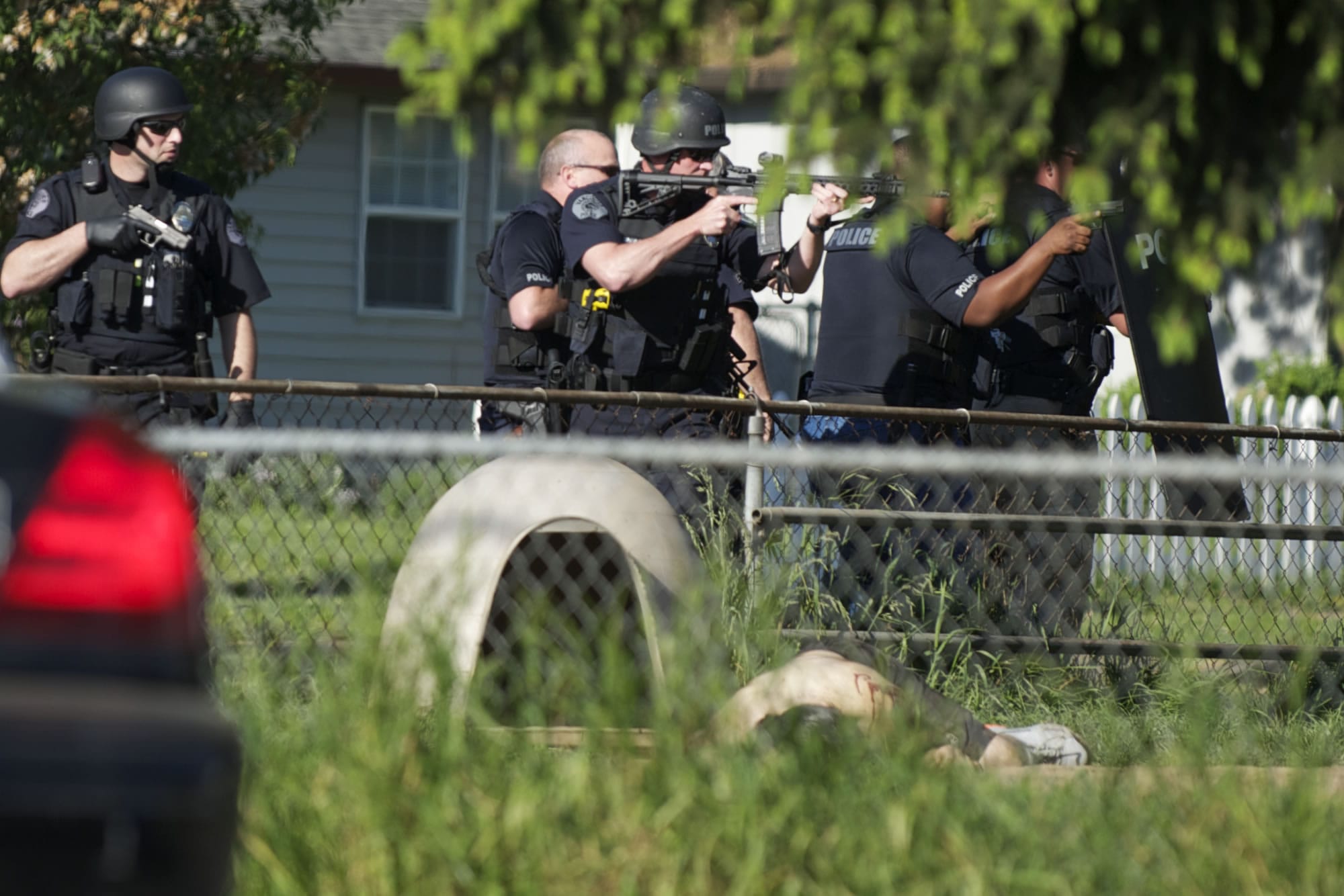 Police officers move in, weapons drawn and deploying a shield, to secure a shooting scene enough to allow medics to treat a man who'd been shot in the yard of a home in the Fruit Valley neighborhood.