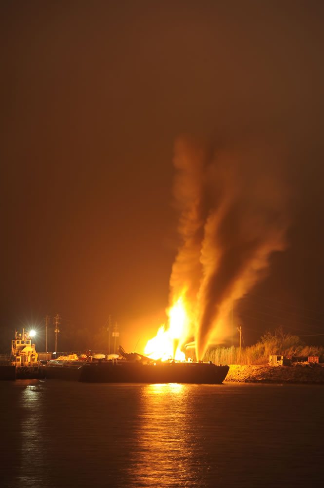 Fire burns aboard two fuel barges along Mobile River after explosions sent three workers to the hospital.
