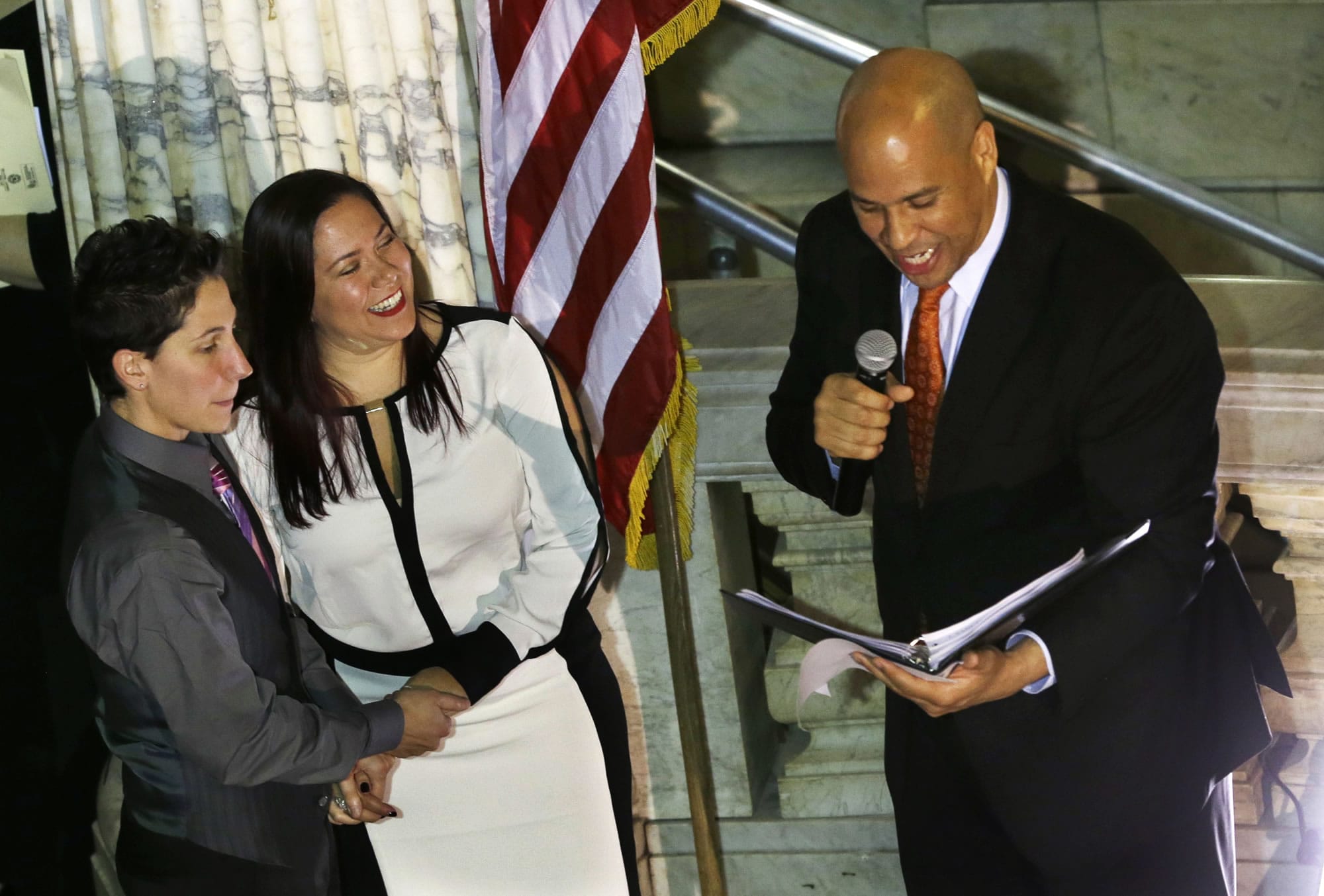 Newark Mayor and Senator-elect Cory Booker, right, officiates the ceremony for the same-sex marriage of Liz Salerno, left, 38, and Gabriela Celeiro, 34, center, at Newark City Hall just after midnight Monday.