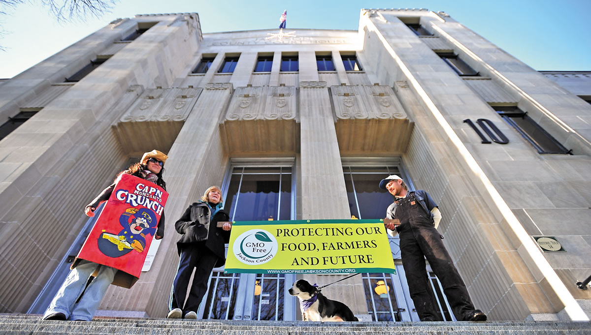 December Tueller, of Ashland, Ore., from left, Caroline White, of Central Point, Ore., and Brand Schilling, of Ashland, Ore., protest genetically modified organisms on the steps of the Jackson County Court House in Medford, Ore., on Wednesday.