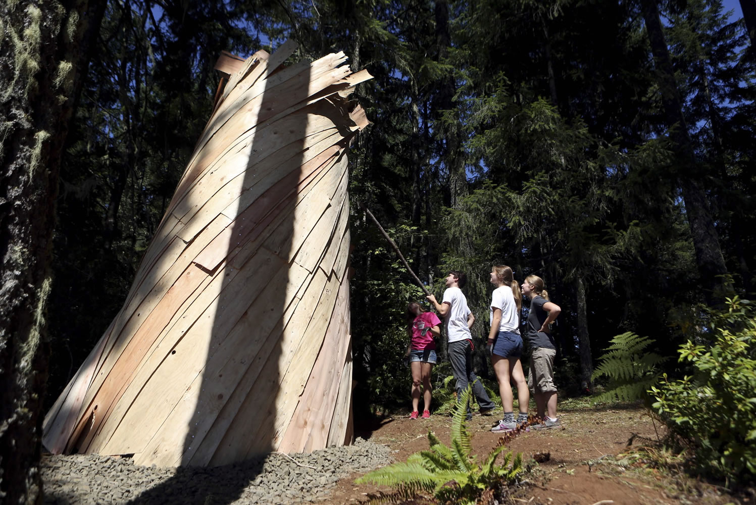 Sonja Ellicott, from left, Caleb Rich, Stephanie Johnson and Courtney Ferris fix some of the thin fir planks surrounding the outside of the massive pinhole camera their class built in the woods Aug.