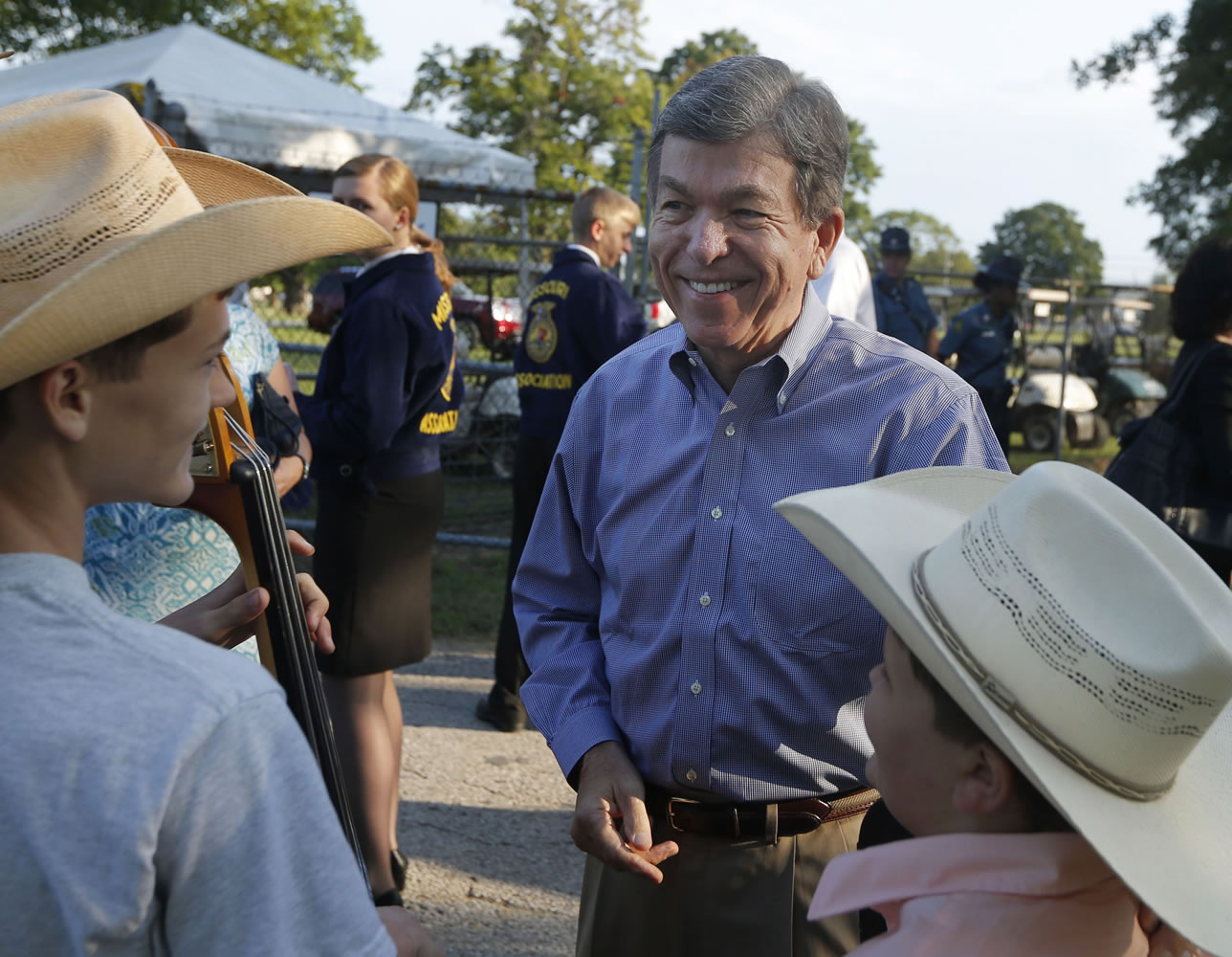 Sen. Roy Blunt, R-Mo., center, greets Trustin Baker, left, and Elijah Baker while attending the Governor's Ham Breakfast at the Missouri State Fair in Sedalia, Mo., on Aug.