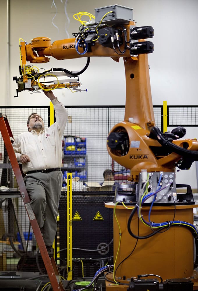 In this Jan. 15, 2013, photo, Rosser Pryor, Co-owner and President of Factory Automation Systems, examines a new high-performance industrial robot at the company's Atlanta facility. Pryor, who cut 40 of 100 workers since the recession, says while the company is making more money now and could hire ten people, it is holding back in favor of investing in automation and software.