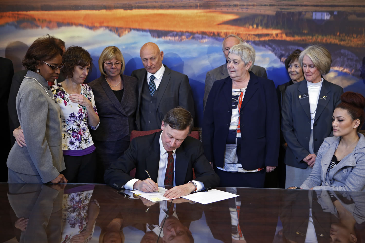 Sponsors and family members of victims watch as Colorado Gov. John Hickenlooper signs control bills into law at the Capitol in Denver on Wednesday.