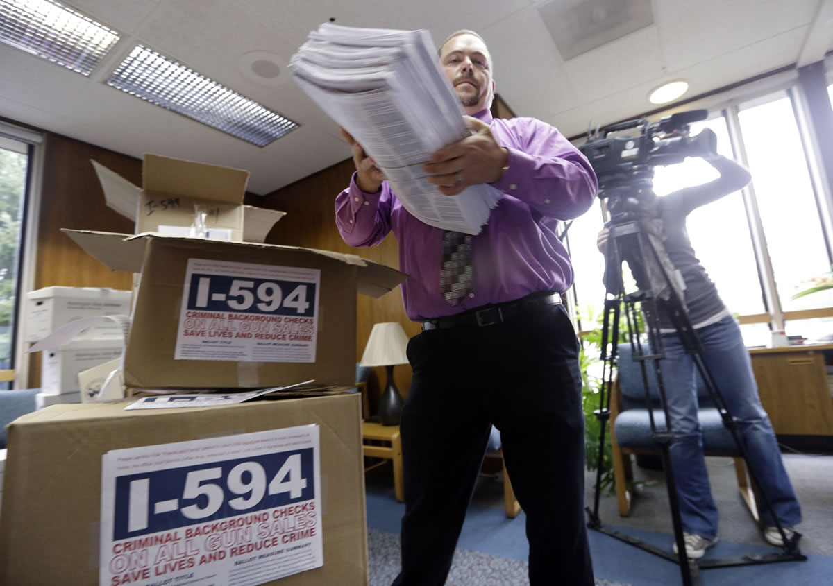 Elections worker Joseph MacLean lifts petitions for Initiative 594 from a box as he prepares them to be counted at the Secretary of State's office Wednesday, Oct. 9, 2013, in Olympia, Wash. Advocates seeking to expand the use of background checks on gun sales in Washington state turned in more than 250,000 signatures for the initiative, the first batch of petitions they plan to submit before a January deadline to qualify it to the Legislature.
