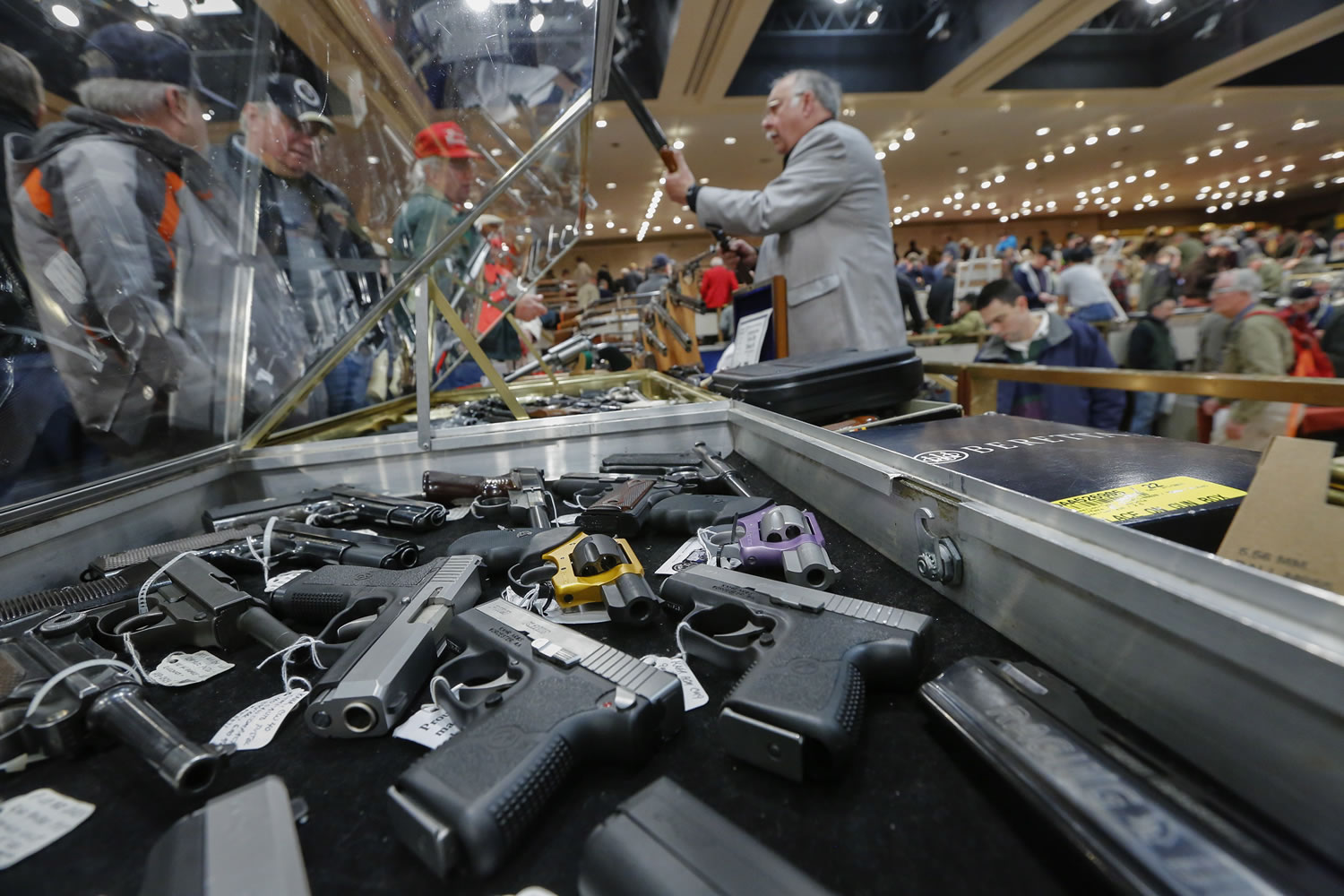 Handguns appear on display at the table of David Petronis of Mechanicville, N.Y., standing with rifle, who owns a gun store, during the heavily attended annual New York State Arms Collectors Association Albany Gun Show at the Empire State Plaza Convention Center in Albany, N.Y.