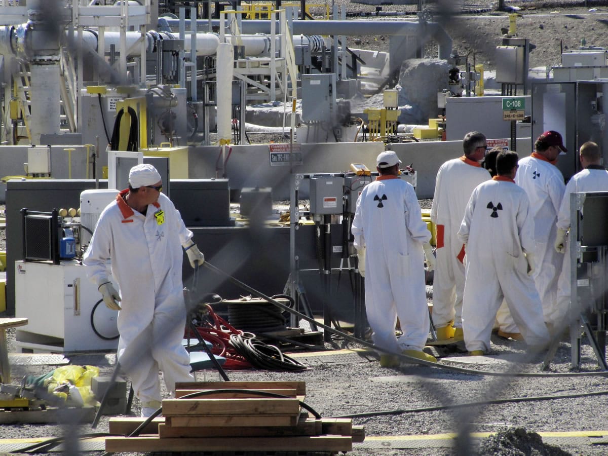 Workers at the Hanford nuclear reservation work around a tank farm where highly radioactive waste is stored underground near Richland in 2010.