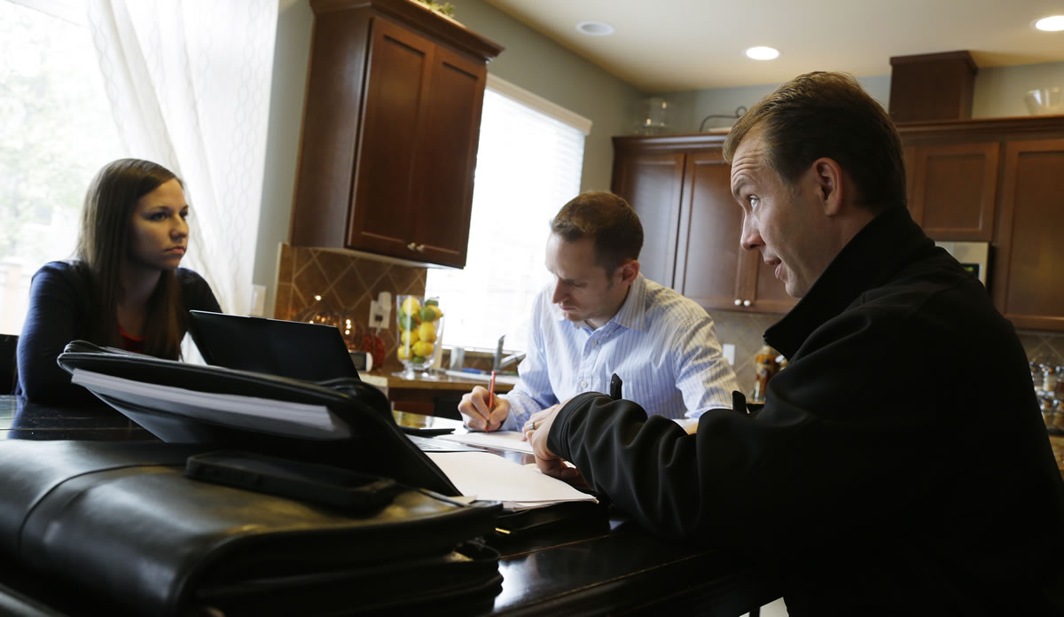 Insurance broker Jeff Lindstrom, right, meets with Brandi and Darren Litchfield to discuss health insurance plan options, at their home in the Seattle suburb of Bothell.
