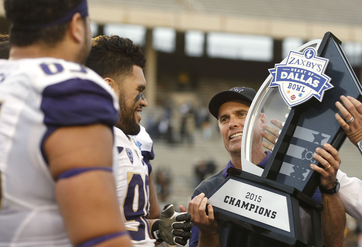 Washington head coach Chris Petersen celebrates with players including Washington defensive lineman Taniela Tupou (90) after Washington's 44-31 victory over Southern Mississippi at the Heart of Dallas Bowl NCAA college football game, Saturday, Dec. 26, 2015, in Dallas.