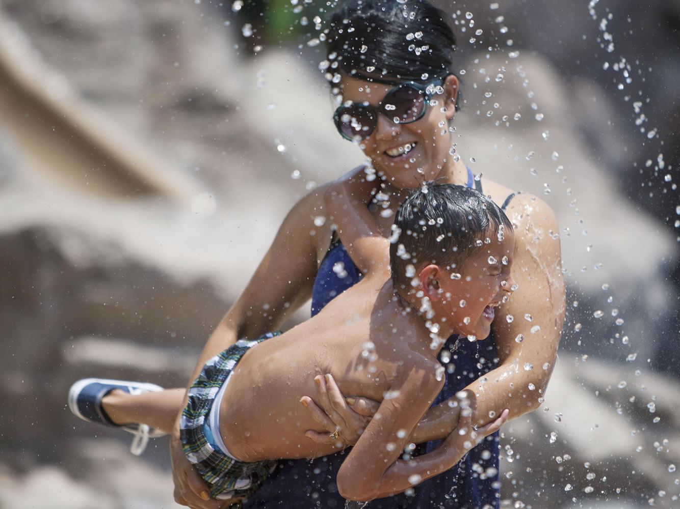 Alma Azpeitia holds nephew Aidan Azpeitia, 4,  in the splash pad at Tempe Beach Park on Saturday in Tempe, Arizona.