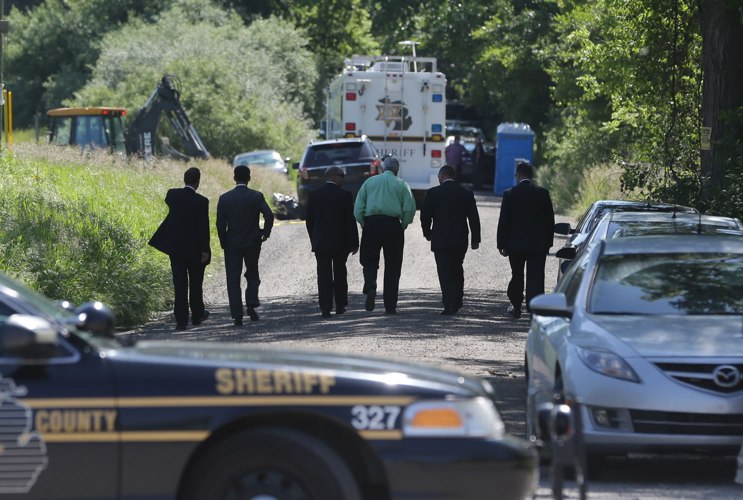 Law enforcement officials walk back to the search area after Robert Foley, special agent in charge of the FBI's Detroit division, addressed the media in Oakland Township, Mich., on Wednesday and announced the FBI was ending the search operations for the remains of Teamsters union president Jimmy Hoffa who disappeared from a Detroit-area restaurant in 1975.