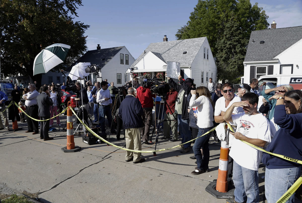 Media and spectators watch as authorities drill for soil samples beneath the shed of a home in Roseville, Mich., on Friday.