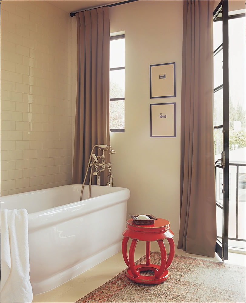 A neutral master bath is brightened with a vintage, Chinese burnt orange garden stool.