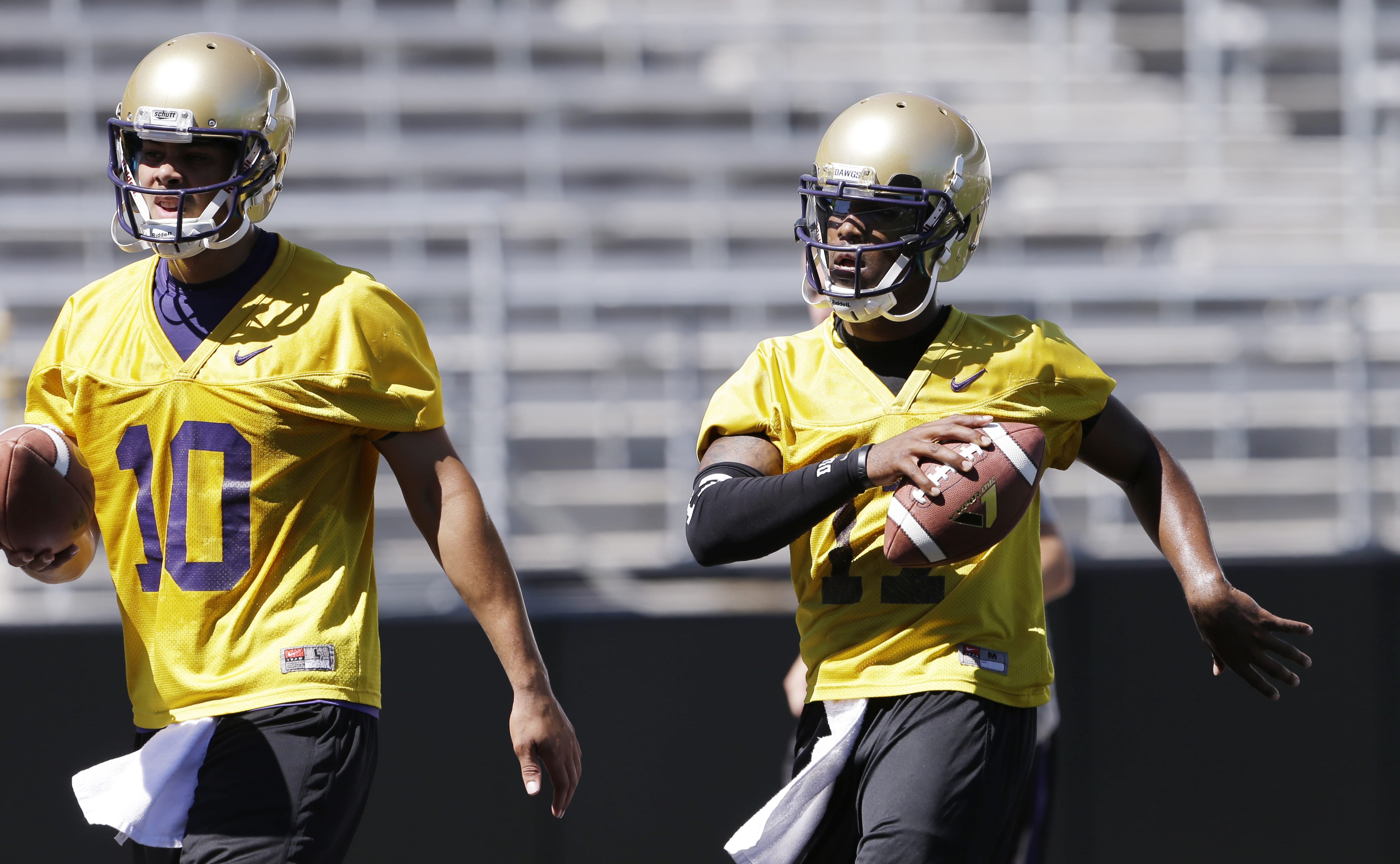 Washington quarterback Keith Price, right, and Cyler Miles runs at the team's first football practice Monday, Aug.