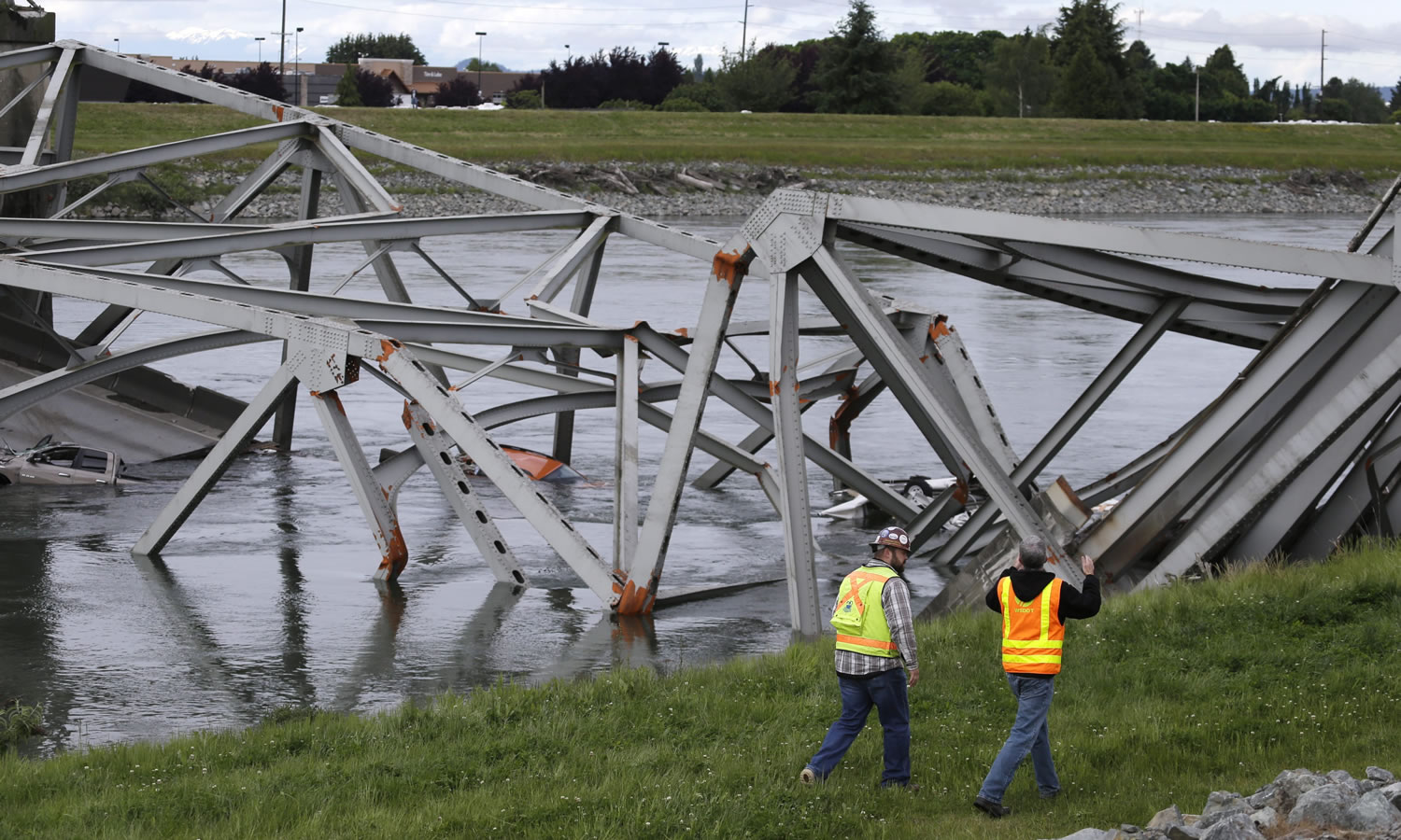 Workers walk past the collapsed portion of the Interstate 5 bridge at the Skagit River on Friday.
