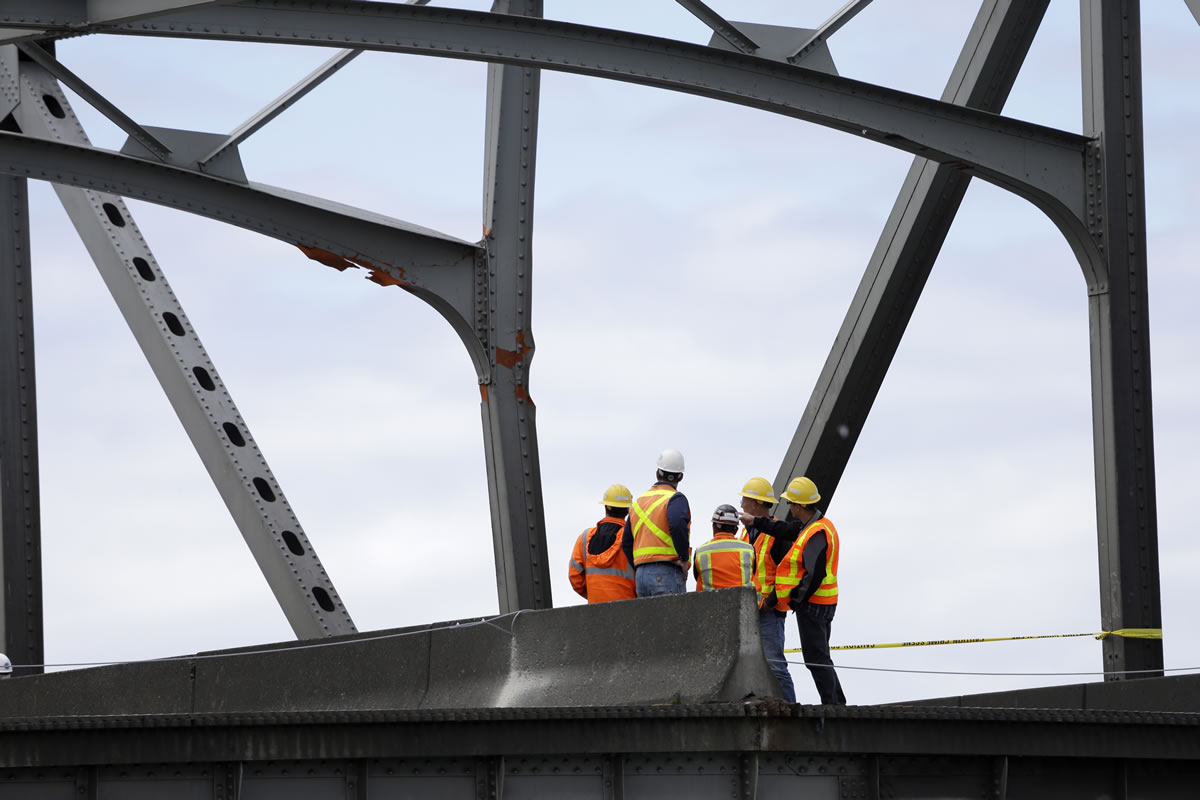 Workers look up at a damaged beam on a section of bridge adjacent to a collapsed portion of the Interstate 5 bridge at the Skagit River on Friday in Mount Vernon.