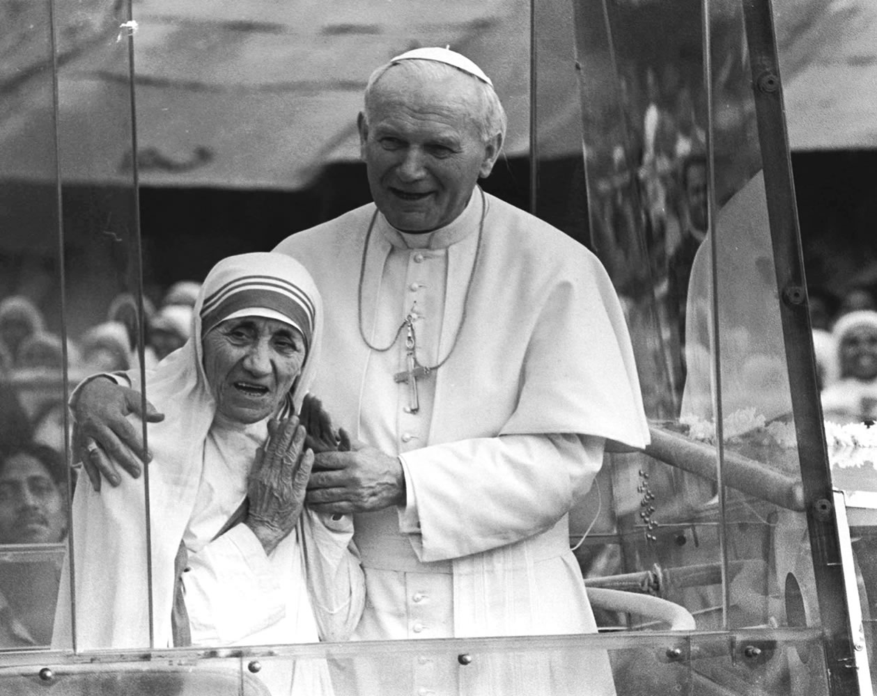 Pope John Paul II holds his arm around Mother Teresa in February 1986 as they ride in the Popemobile outside the Home of the Dying in Kolkata, India. Mother Teresa, the tiny stooped nun who cared for the poorest of the poor in the slums of India and beyond, will be declared a saint next year after Pope Francis approved a miracle attributed to her intercession.