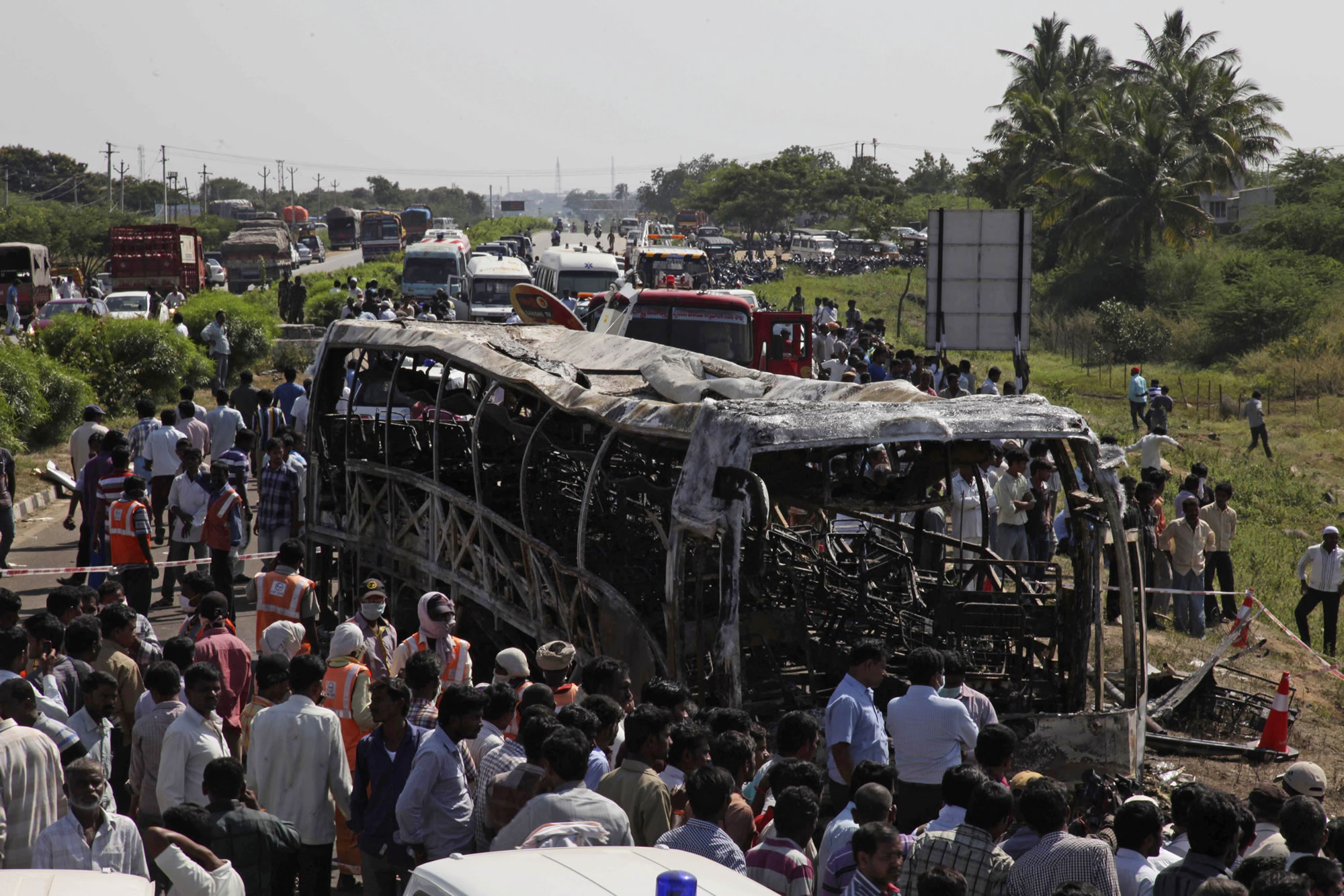 Rescuers and others gather near the wreckage of a bus that crashed into a highway barrier and erupted in flames Wednesday in southern Andhra Pradesh state, India.