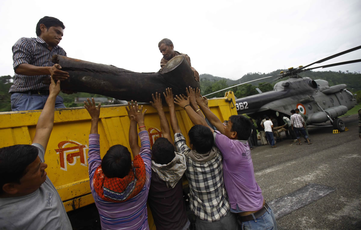 Locals unload a large piece of wood from a truck to be placed on to an Indian Air force helicopter as cremation efforts for those killed in landslides and monsoon floods are underway, in Gauchar, in northern Indian state of Uttarakhand, on Tuesday.