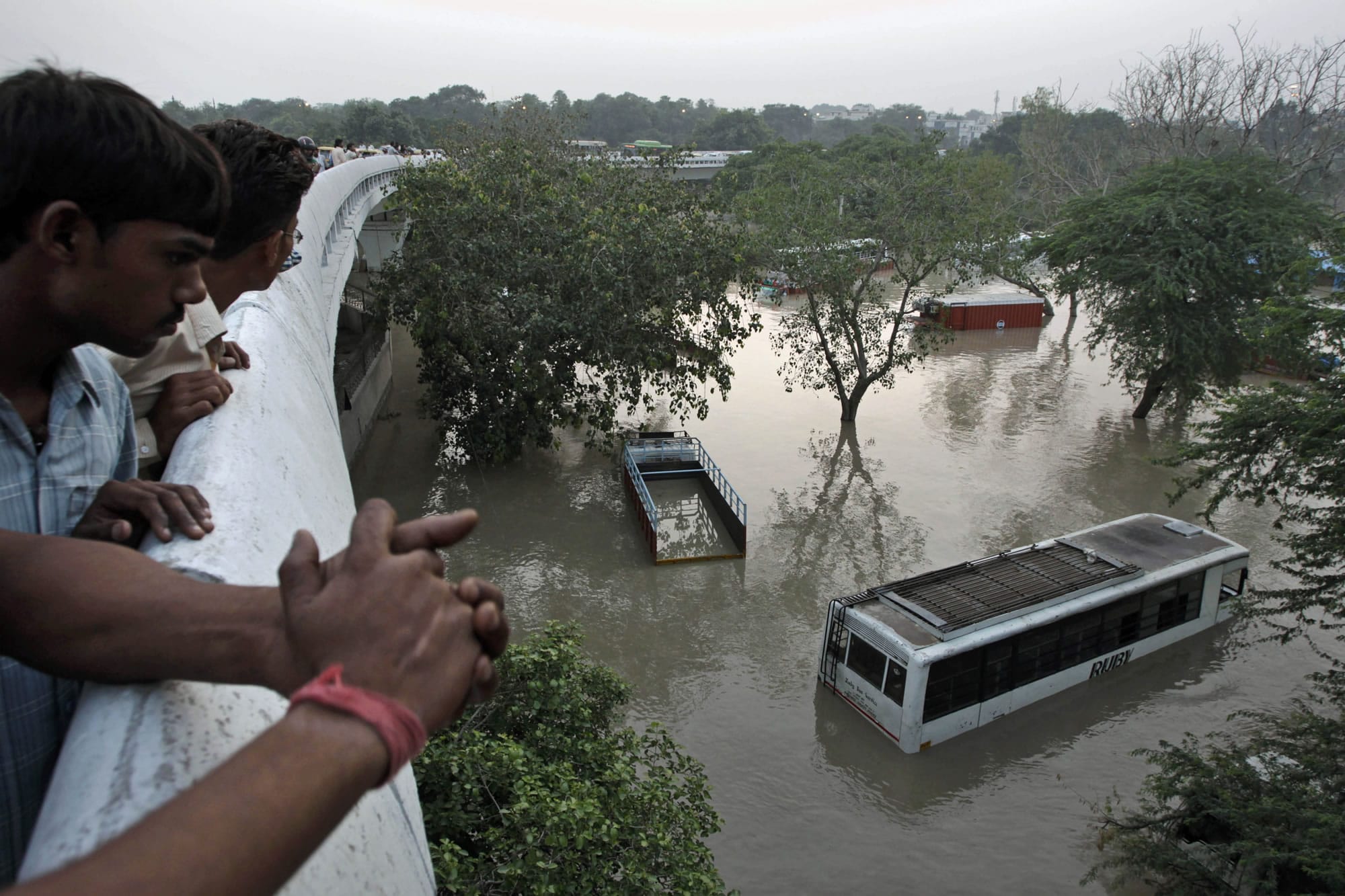 People gather to look at submerged buses and trucks in the rising Yamuna River as they stand on a flyover in New Delhi, India, on Wednesday.