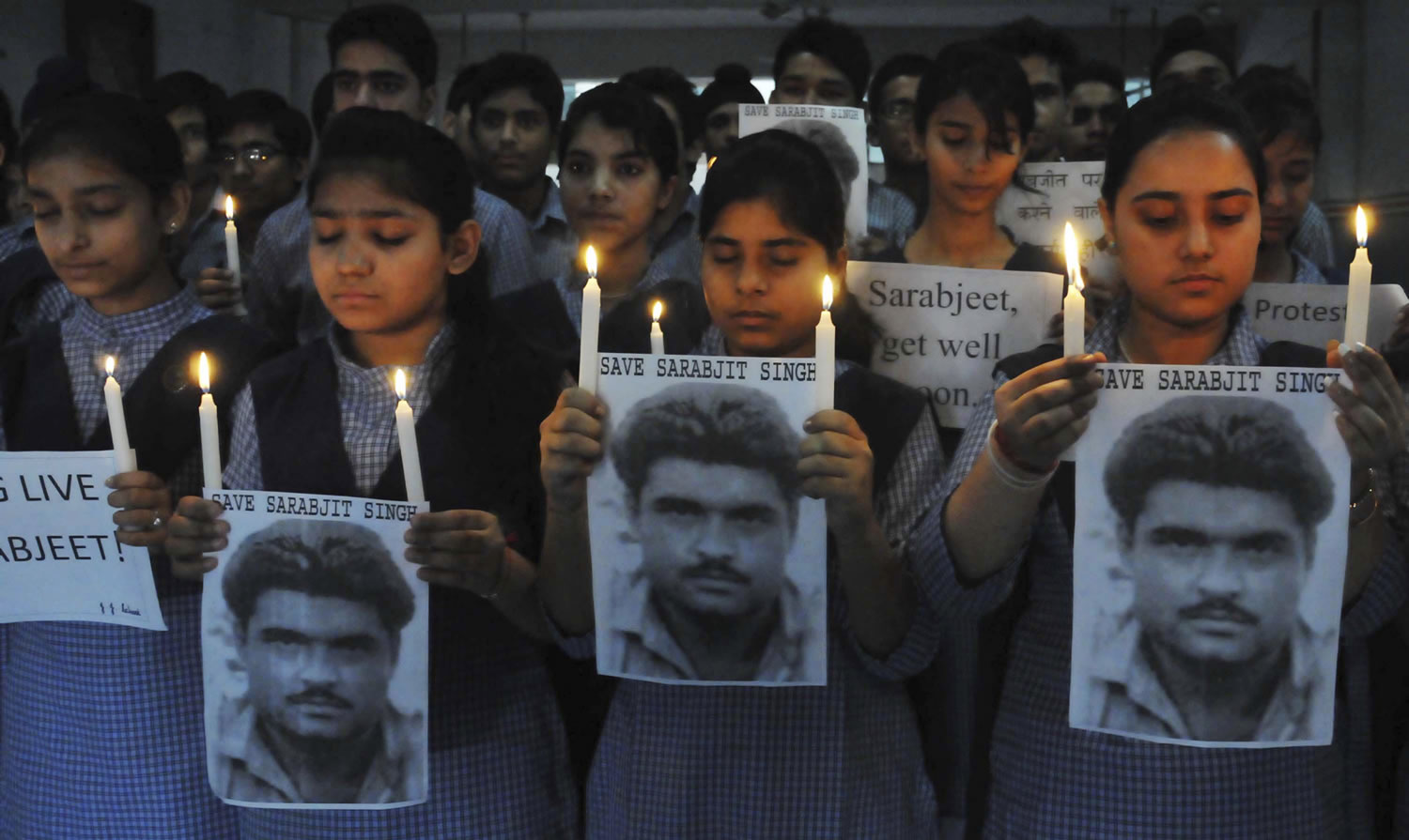 Indian school children hold photographs of Sarabjit Singh, an Indian spy on death row in Pakistan as they light candles and pray for his recovery in Amritsar, India, on Monday.