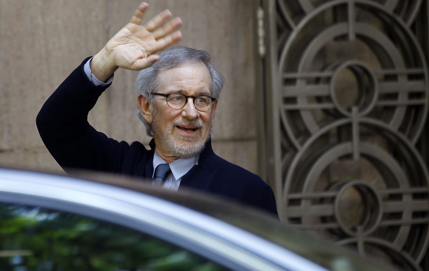 Director Steven Spielberg waves to the media as he leaves Indian Industrialist Anil Ambani's office in Mumbai, India, on Monday.