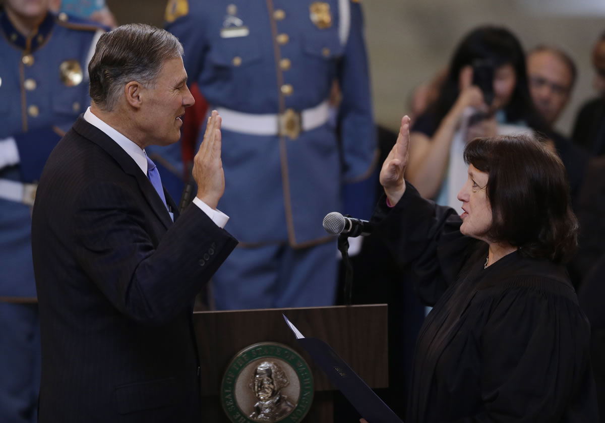 Jay Inslee, left, is sworn in as Washington state governor Wednesday by Washington Supreme Court Chief Justice Barbara Madsen in the rotunda of the Legislative Building at the Capitol in Olympia.