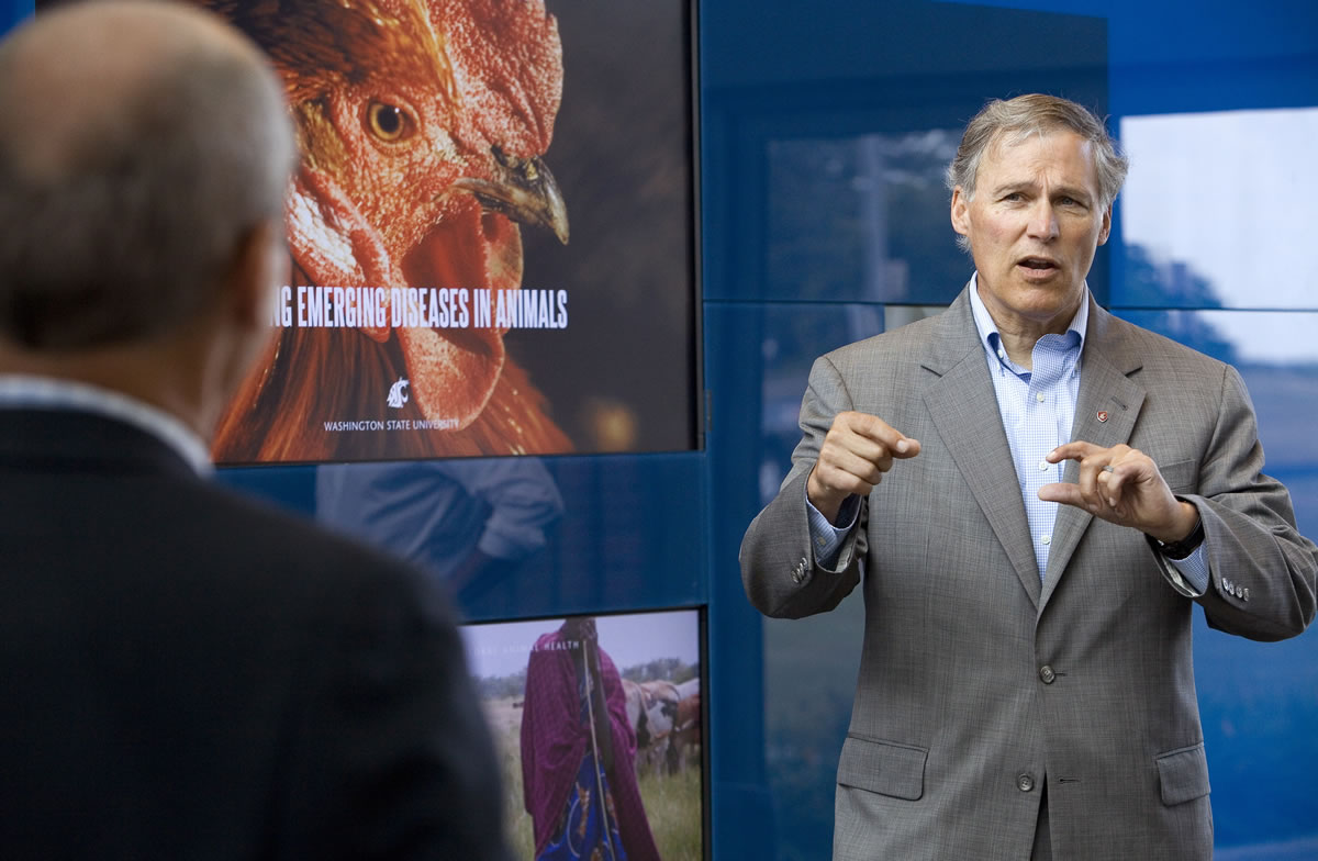Washington Gov. Jay Inslee, right, asks Tim Baszler a question during a tour of the Paul G.