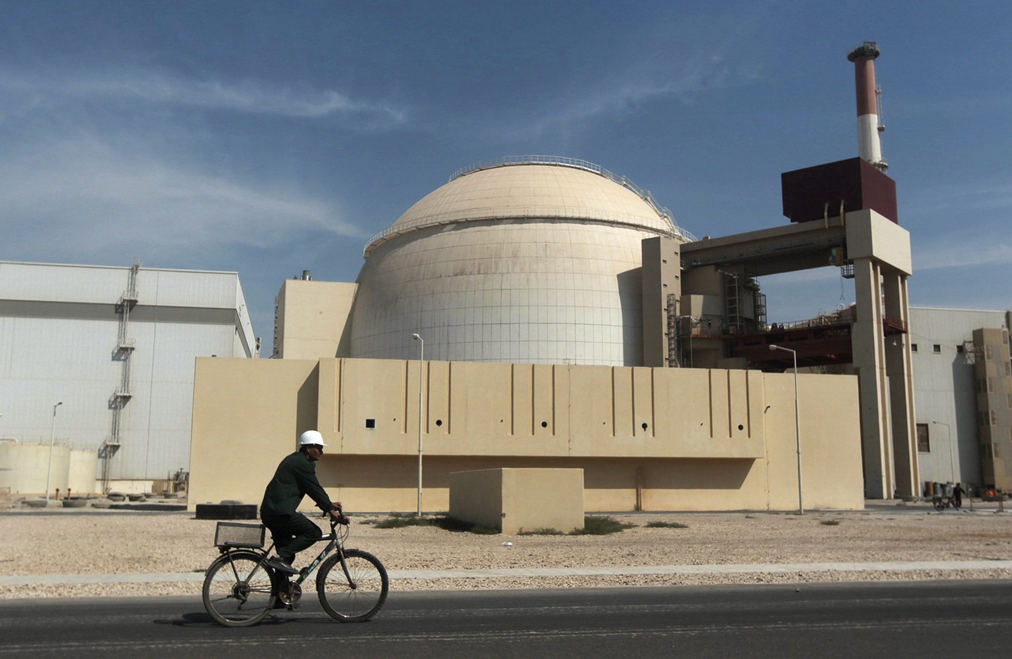 A worker bikes past the reactor building of the Bushehr nuclear power plant outside Bushehr, Iran, in October 2010.