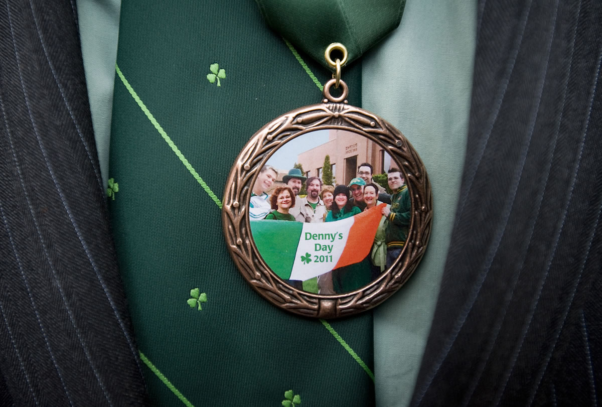 As seen in a medallions's reflection, family and friends of the late Denny Lane raise the Irish flag in his honor on St. Patrick's Day 2011 at the Clark County Courthouse.