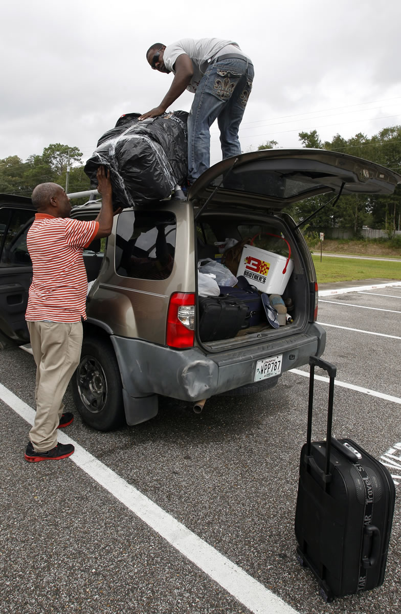 Santos Valerio, left,  helps Santos Rodriguez get luggage from their car Tuesday as they seek shelter at the Theodore High School in Theodore, Ala. after leaving Metairie, La. The U.S. National Hurricane Center in Miami said Isaac became a Category 1 hurricane Tuesday with winds of 75 mph.