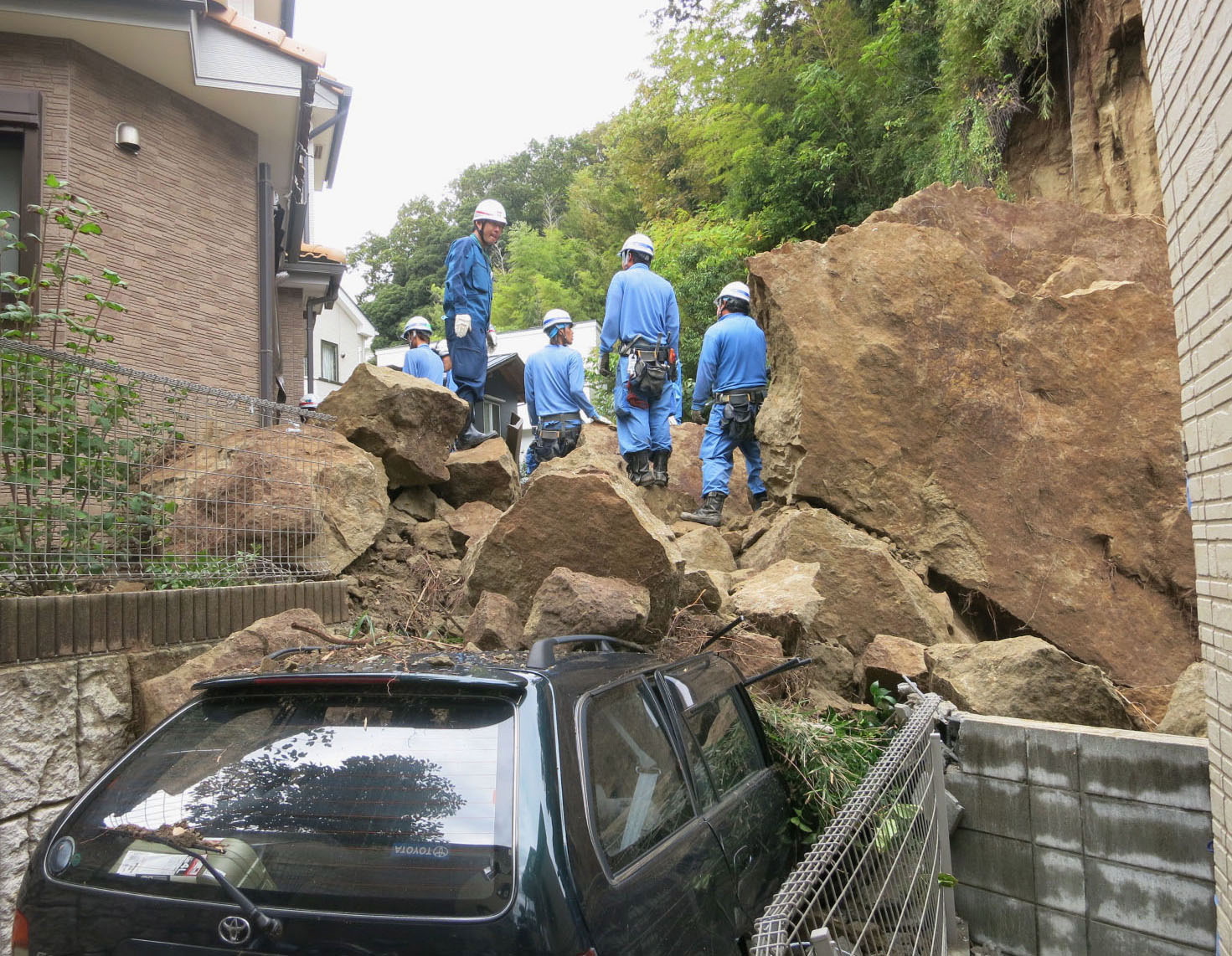 Firefighters stand on rocks fallen from a cliff over a garage and a road in a residential area in Kamakura, southwest of Tokyo, after a powerful typhoon hit Japan's metropolitan area Wednesday morning.