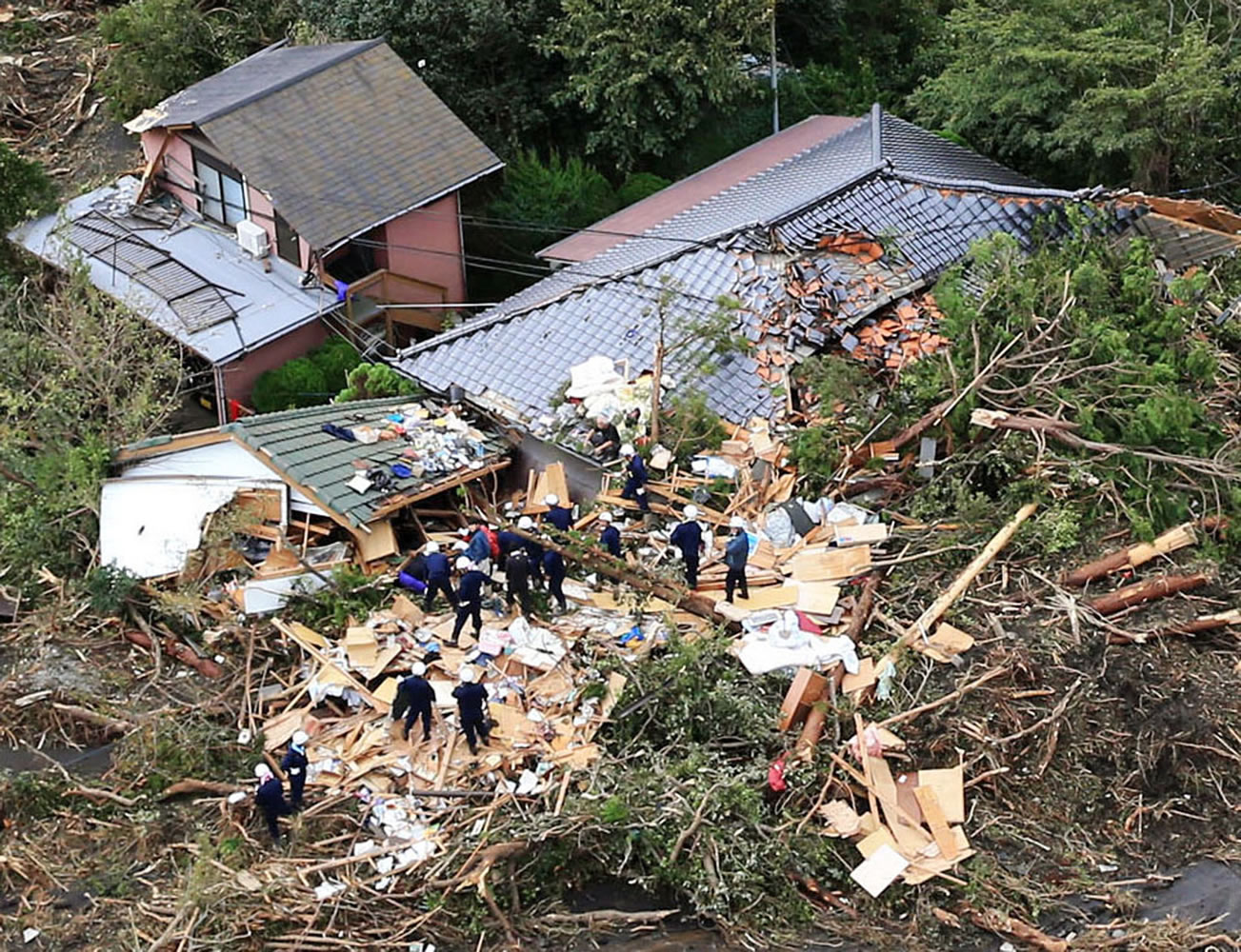 Rescue workers look for survivors as they stand on the rubble of a house buried by mudslides after a powerful typhoon hit Oshima on Izu Oshima island, about 120 kilometers (75 miles) south of Tokyo on Wednesday morning.